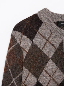 Detailed macro view showing soft knit texture and brown argyle pattern on women's sweater