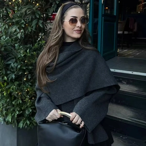 Detail of dark charcoal knit coat with asymmetric scarf collar and gold handle leather bag