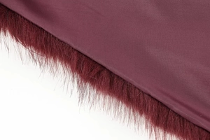 Detailed macro shot of deep red fabric texture with faux fur trim and fine stitching