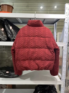 Detaillierte Nahaufnahme der dunkelroten Pufferjacke mit Zopfstrickmuster und Stehkragen