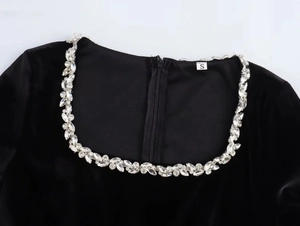 Detail of square neckline with silver rhinestones on black velvet dress with back zipper