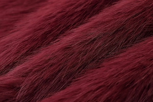 Macro detail of wine red faux fur fabric with smooth texture and glossy silk-like finish