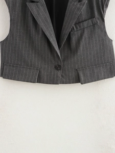 Close-up detail of dark grey pinstripe vest showing tailored lapel and button closure