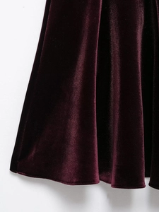 Close-up of wine red velvet fabric texture and hem detailing on a sleeveless dress