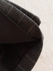 Detailed macro view of dark grey pinstripe fabric texture with smooth black inner lining