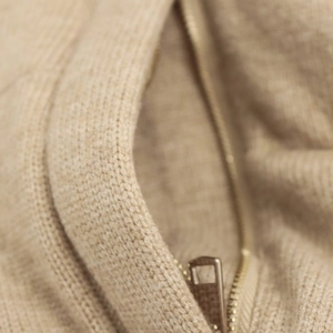 Détail d'une veste en maille beige avec fermeture éclair en métal doré clair