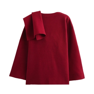 Detailed close-up of dark red knitted coat with asymmetric scarf shoulder detail