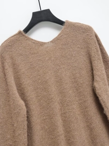 Gros plan sur la texture du pull en maille marron col V sur un cintre noir sur fond blanc
