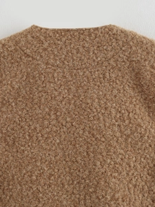 Close-up macro detail of the warm camel bouclé textured fabric and fine stitching