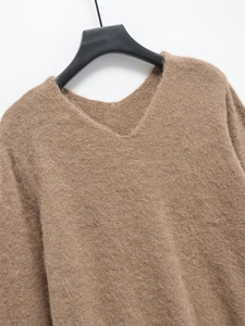 Gros plan sur la maille épaisse d'un pull camel à col en V avec une texture douillette