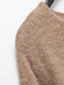 Gros plan du tissu d'un pull en mohair camel montrant la texture douce et duveteuse