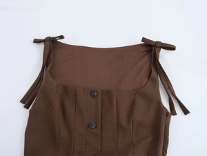 Detailed view of brown houndstooth dress featuring bow straps and decorative buttons