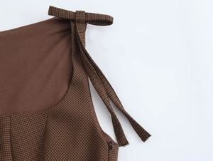 Detail of brown houndstooth dress featuring tie-up shoulder straps and hidden side zipper