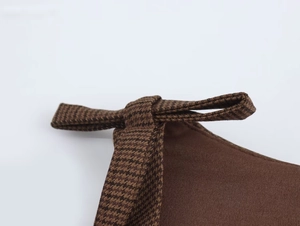 Detail of dark brown dress featuring a houndstooth bow knot decoration in coffee and black