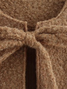 Detailed close-up of a brown fleece vest featuring a soft bow tie and fuzzy wool texture