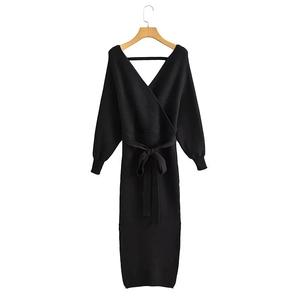 Detail view of the black knit dress showing the V-neckline and tie waist belt