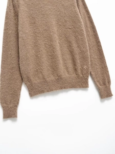 Gros plan sur la texture en tricot beige doux et l'ourlet côtelé du pull en laine