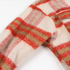 Detailed view of thick red and beige plaid flannel fabric with a pocket on the jacket