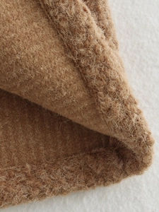 Macro detail of camel wool fabric texture and fine stitching on a premium autumn vest