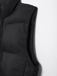 Detail shot of the armhole and shoulder of a shiny black padded vest with quilted padding