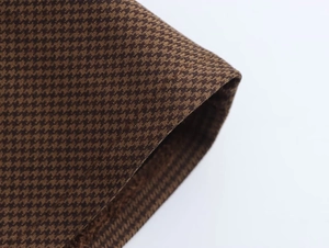 Detailed macro view of the premium brown houndstooth fabric pattern on a dress