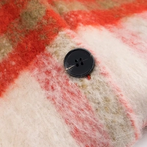 Detail of warm plaid wool fabric with soft plush texture and black button closure