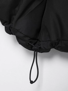 Close-up of black puffer vest hem featuring adjustable elastic drawstring and plastic stopper