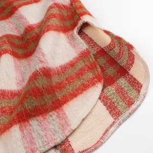 Detail of red and brown plaid coat featuring fuzzy texture and side slit curved hem