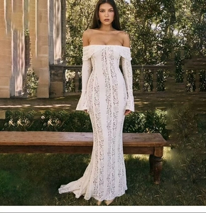 Close-up of white off-shoulder lace dress with intricate crochet detailing and flared sleeves