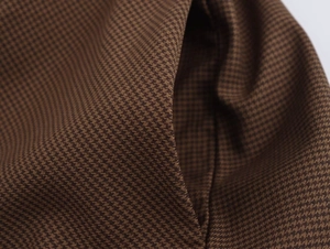 Macro view of the classic brown and black houndstooth pattern on a thick dress fabric