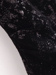 Dettaglio del tessuto in velluto nero con paillettes lucide e una trama di lusso