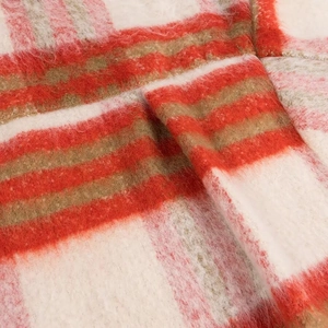 Close-up of red and white plaid wool blend fabric showing thick texture and soft fibers