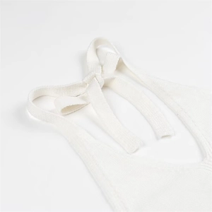 Close-up of white knitted halter neck tie detail showing refined fabric texture and knot