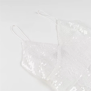 Dettaglio dell'abito in pizzo bianco con paillettes scintillanti e sottili spalline con scollo a V