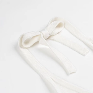 Detail of the white knitted halter neck top featuring a delicate bow tie strap design