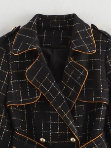 Detail of tweed coat featuring orange trim, gold buttons and metallic plaid texture