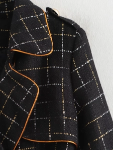 Detailed macro view of black tweed fabric texture with gold trim and metal buttons