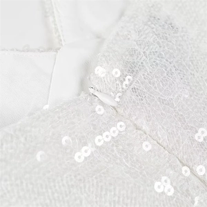 Dettaglio macro di una cerniera invisibile su un abito bianco con pizzo e paillettes