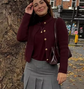 Detail of burgundy knitted cardigan with golden embossed buttons in street style look