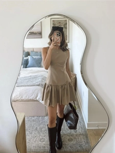 Beige sleeveless dress with pleated skirt and low waist shown in a lifestyle mirror shot