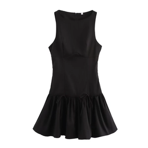 Detail of a black sleeveless dress showing the pleated ruffle hem and drawstring bow accents
