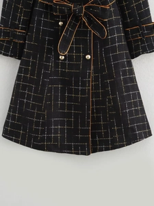 Detail of tweed fabric with gold mesh lines and vintage buttons on a black coat