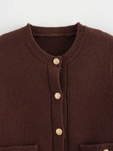 Detail view of dark brown knitted cardigan with round neck and gold embossed buttons