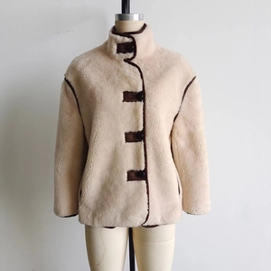Detail of cream faux shearling jacket with brown trim and contrasting button accents