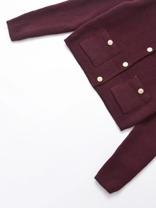 Macro detail of wine red knit cardigan with textured fabric and golden embossed buttons