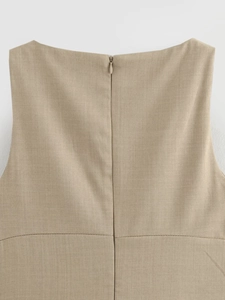 Close-up of the beige sleeveless dress showing the back invisible zipper and fabric texture