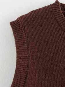 Close-up of deep brown knitted vest showing detailed ribbed neckline and sleeve cuffs texture