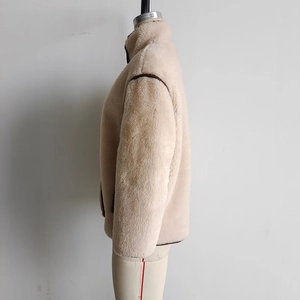 Detail of faux fur jacket featuring warm fleece texture and dark brown leather piping