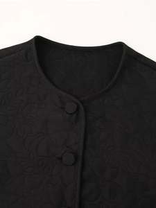 Close-up of floral embossed quilting and fabric buttons on black round neck jacket