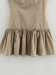 Detailed view of the khaki dress featuring elegant ruffle hem and decorative bow tie knots
